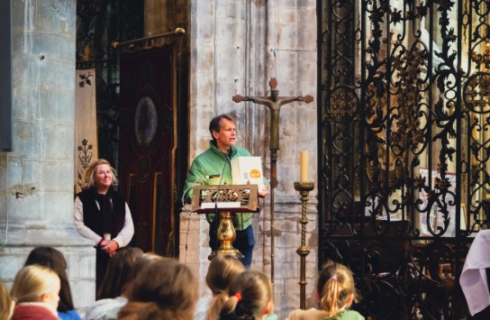 Man spreekt voor groep kinderen in de kerk van Alsemberg. (vergroot foto)