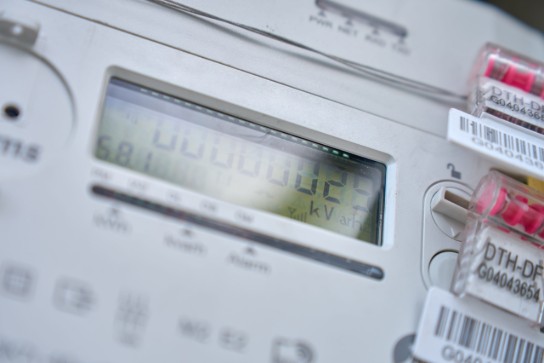 Digitale elektriciteitsmeter met display en beveiligde aansluitingen met rode verzegeling. (vergroot foto)