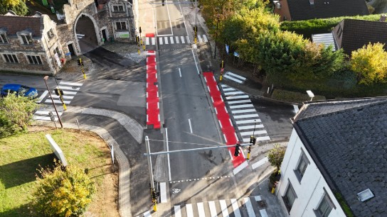 Luchtfoto van een kruispunt met rode fietsstroken, zebrapaden, verkeerslichten en een historische stadspoort. (vergroot foto)