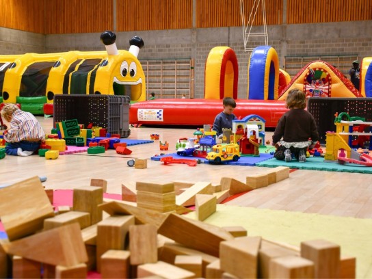 Kinderen spelen met blokken en speelgoed in een binnenspeeltuin met springkussens. (vergroot foto)
