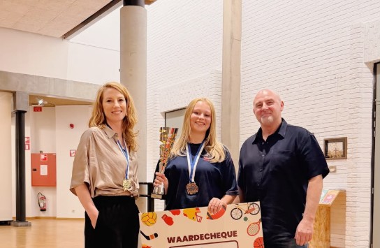 Drie mensen, waaronder de sportbelofte van het jaar, poseren met een trofee, medailles en een waardebon van 200 euro in een zaal. (vergroot foto)